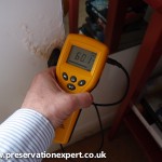 An electronic moisture meter reads qualitative on plaster