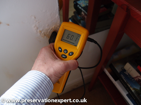 An electronic moisture meter reads qualitative on plaster